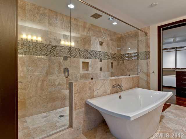 139 South Tryon Street, Unit 3B Charlotte, NC 28202 - Photo 11 of 16 a white bath tub sitting in a bathroom and shower