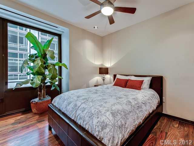 139 South Tryon Street, Unit 3B Charlotte, NC 28202 - Photo 14 of 16 a bedroom with a bed and a potted plant