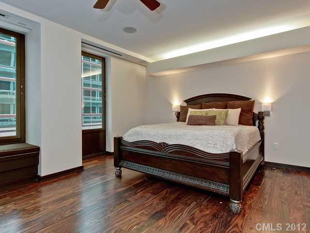 139 South Tryon Street, Unit 3B Charlotte, NC 28202 - Photo 10 of 16 a bedroom with a bed and wooden floor
