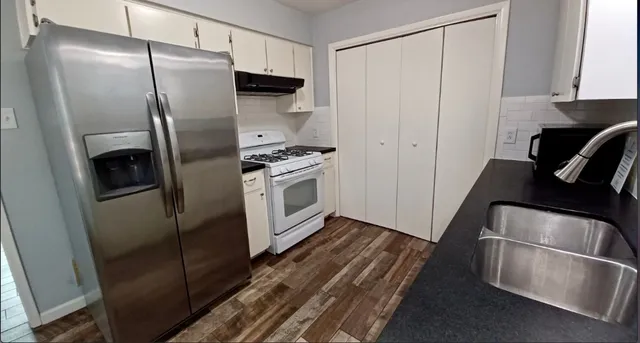 a kitchen with stainless steel appliances granite countertop a refrigerator a stove and a sink