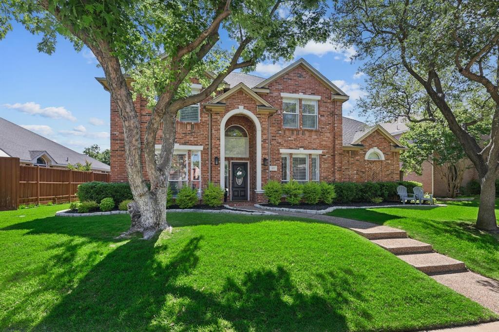a front view of a house with a garden and trees