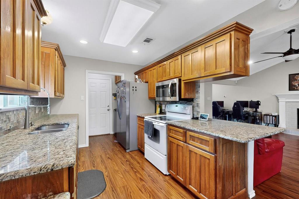 6617 Whitley Road Watauga, TX 76148 - Photo 11 of 36 a kitchen with stainless steel appliances granite countertop a sink stove cabinets and wooden floor
