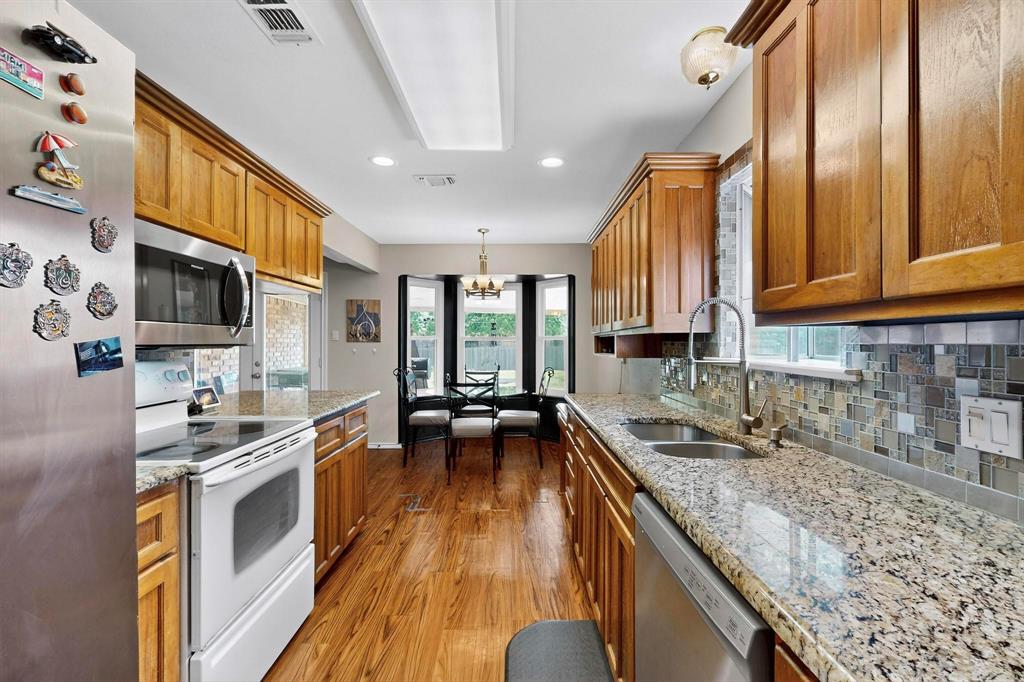6617 Whitley Road Watauga, TX 76148 - Photo 13 of 36 a kitchen with stainless steel appliances granite countertop a stove a sink and a microwave