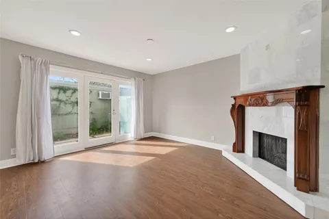 a view of an empty room with wooden floor fireplace and a window