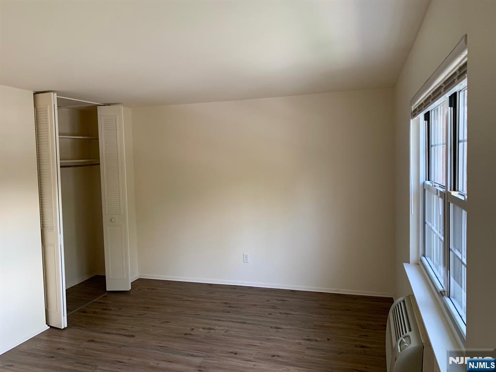 153 Park Avenue, Unit 153C Park Ridge, NJ 07656 - Photo 19 of 21 a view of an empty room with wooden floor and a window
