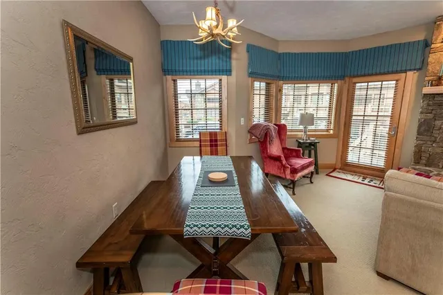 a kitchen with stainless steel appliances granite countertop a stove top oven a refrigerator and chairs with wooden floors