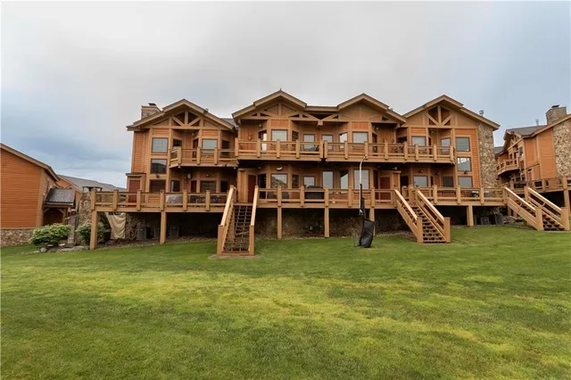 a view of a big house with a big yard and large trees