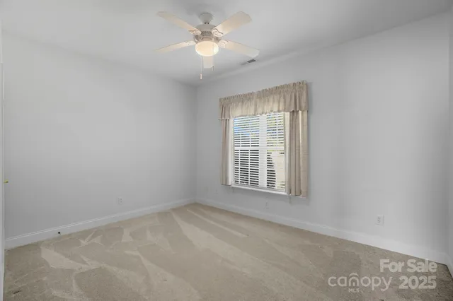 an empty room with a ceiling fan and a window