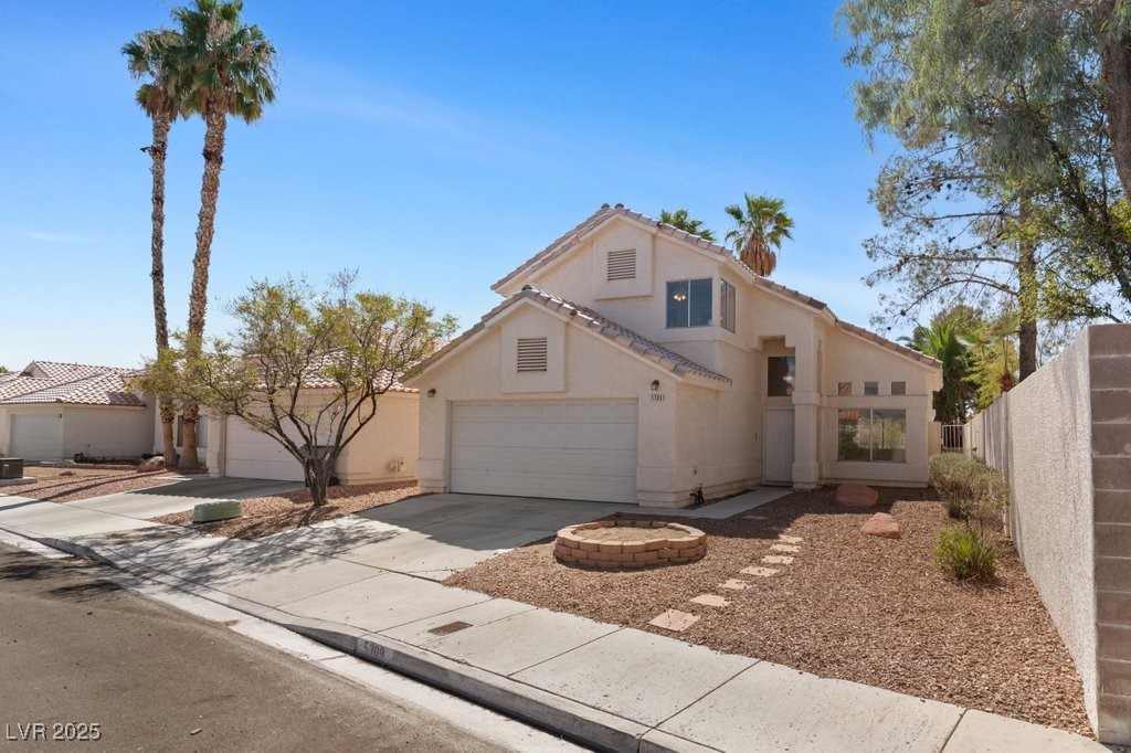 View of front of house with concrete driveway, stucco siding, a tiled roof, and an attached garage