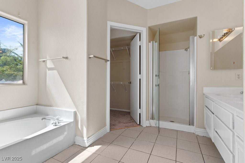 5309 West Camino Del Rancho Las Vegas, NV 89130 - Photo 11 of 41 Full bathroom featuring light tile patterned floors, a stall shower, vanity, a walk in closet, and a garden tub