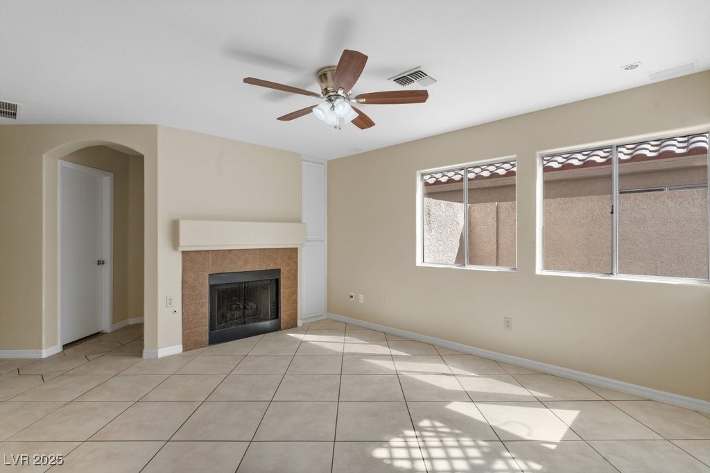 5309 West Camino Del Rancho Las Vegas, NV 89130 - Photo 14 of 41 Unfurnished living room featuring a fireplace, light tile patterned flooring, a ceiling fan, and arched walkways