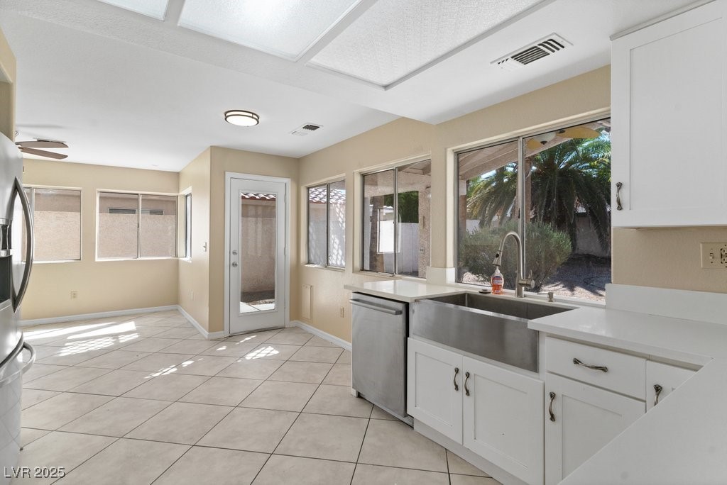 5309 West Camino Del Rancho Las Vegas, NV 89130 - Photo 18 of 41 Kitchen featuring light tile patterned floors, stainless steel appliances, white cabinetry, and light stone counters