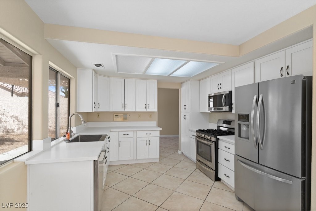 5309 West Camino Del Rancho Las Vegas, NV 89130 - Photo 3 of 41 Kitchen featuring stainless steel appliances, light countertops, light tile patterned floors, and white cabinetry