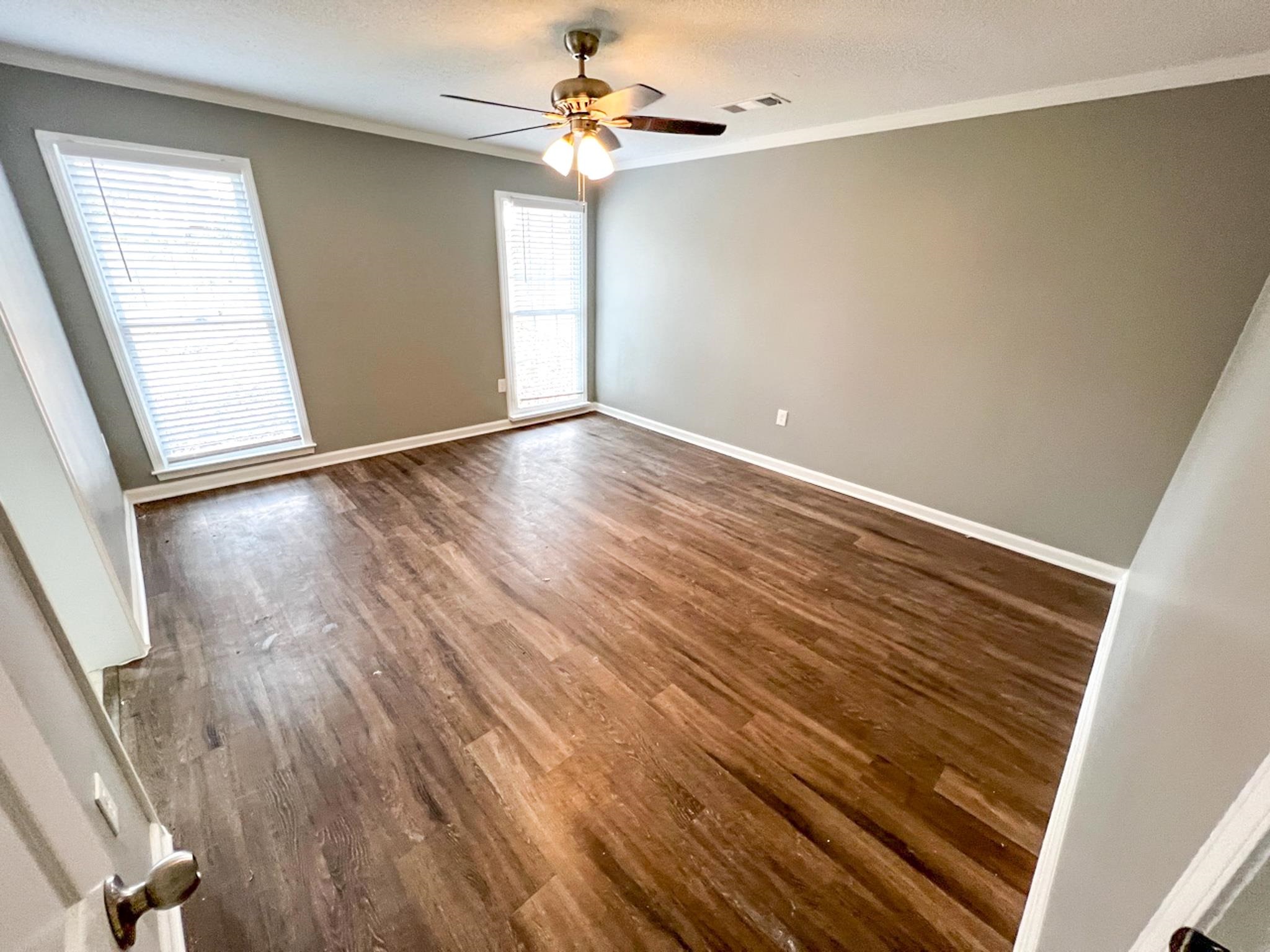 7108 Farmhouse Drive Memphis, TN 38125 - Photo 19 of 21 an empty room with wooden floor chandelier fan and windows