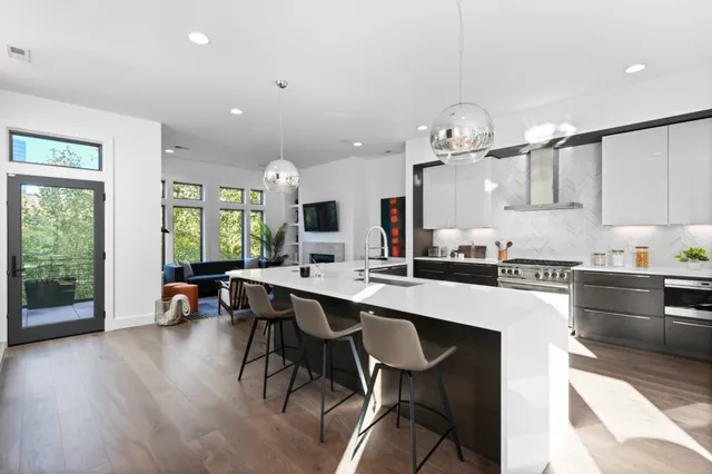 a kitchen with stainless steel appliances a dining table chairs stove and white cabinets