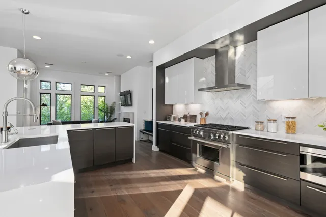 a kitchen with stainless steel appliances kitchen island granite countertop a sink a stove and a wooden floors