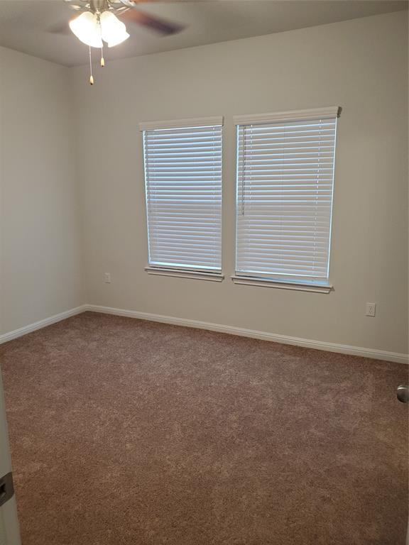6404 Gunflint Drive Austin, TX 78747 - Photo 18 of 21 A well-lit room with warm carpet and two windows, offering a versatile living space.