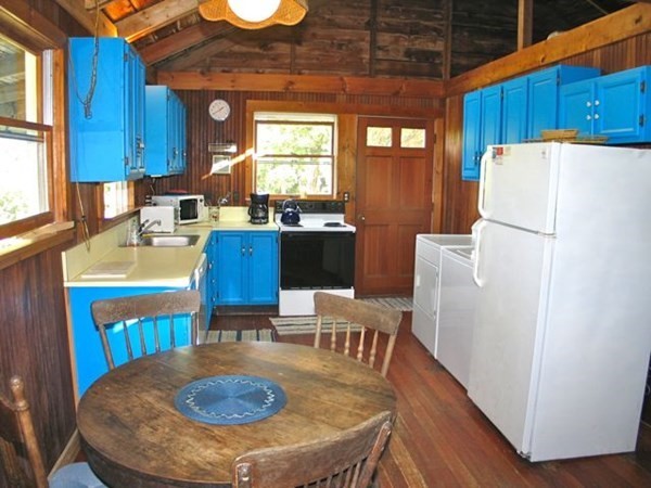 64 Bartimus Luce Road West Tisbury, MA 02568 - Photo 7 of 25 a kitchen with a table chairs and a refrigerator