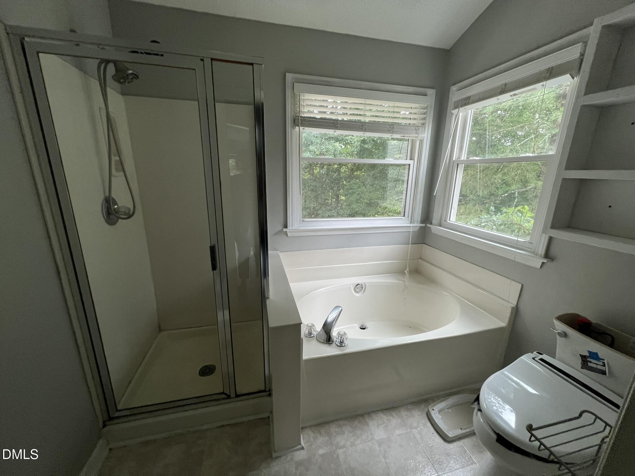 1016 Flower Round Court Raleigh, NC 27610 - Photo 9 of 23 Bathroom featuring a separate walk-in shower with a glass enclosure, a built-in corner soaking tub with deck-mounted fixtures, two windows, and built-in shelving