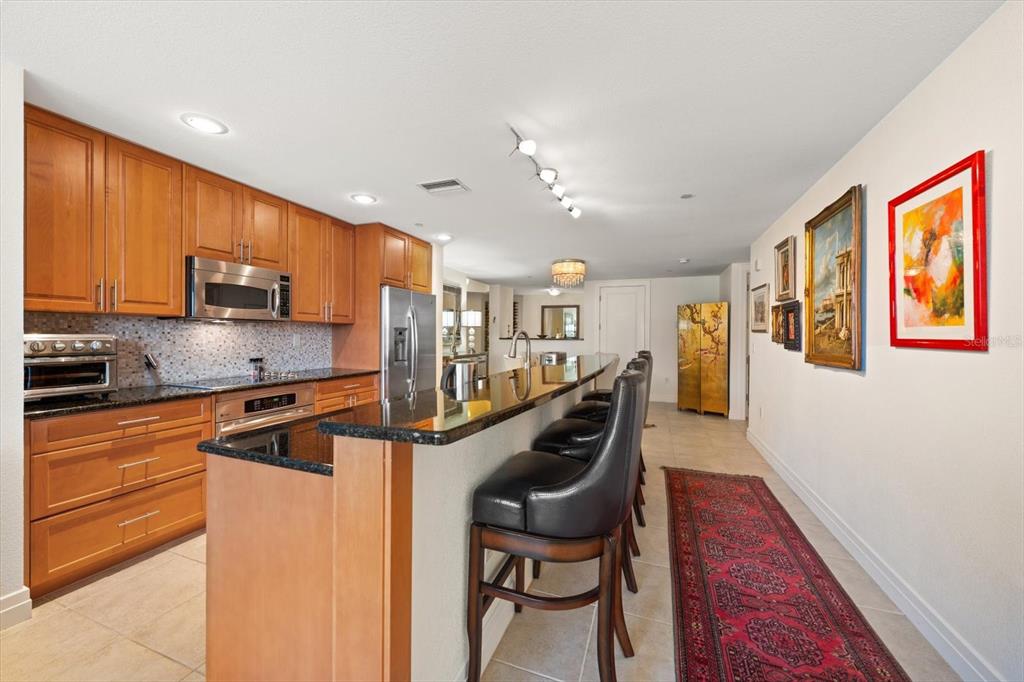 331 Cleveland Street, Unit 301 Clearwater, FL 33755 - Photo 8 of 39 a kitchen with stainless steel appliances granite countertop a refrigerator a stove a sink a dining table and chairs with wooden floor