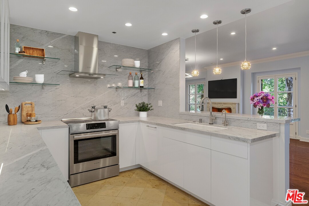 425 North Maple Drive, Unit 304 Beverly Hills, CA 90210 - Photo 12 of 26 a kitchen with stainless steel appliances kitchen island granite countertop a sink and cabinets