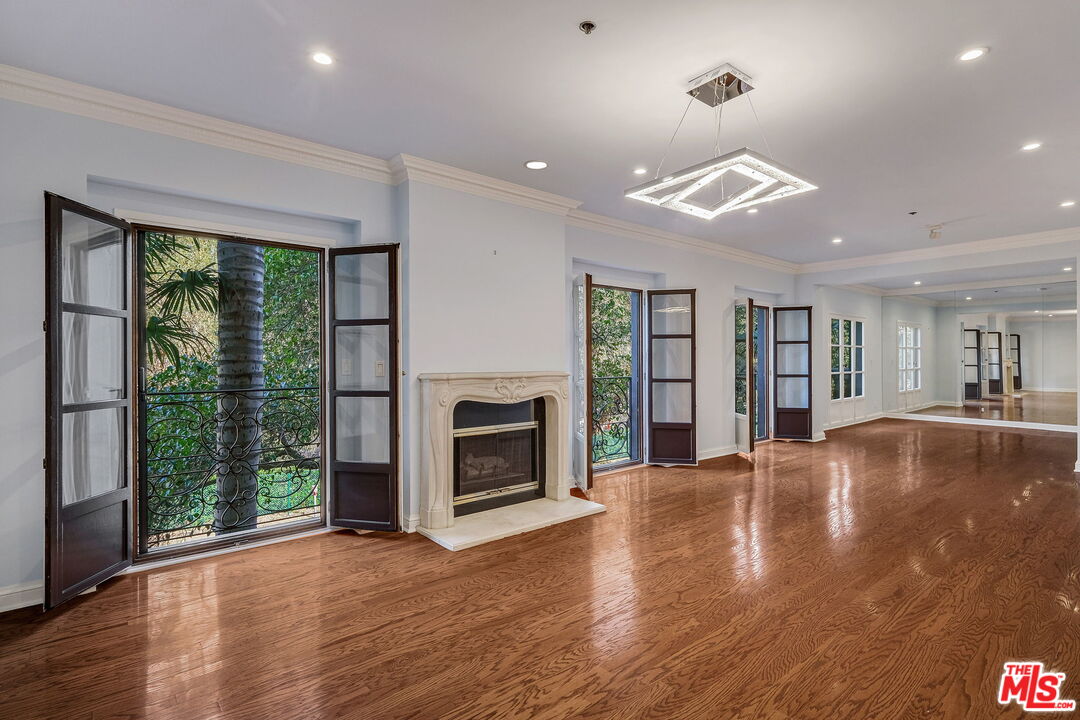 425 North Maple Drive, Unit 304 Beverly Hills, CA 90210 - Photo 5 of 26 a view of an empty room with wooden floor and a fireplace