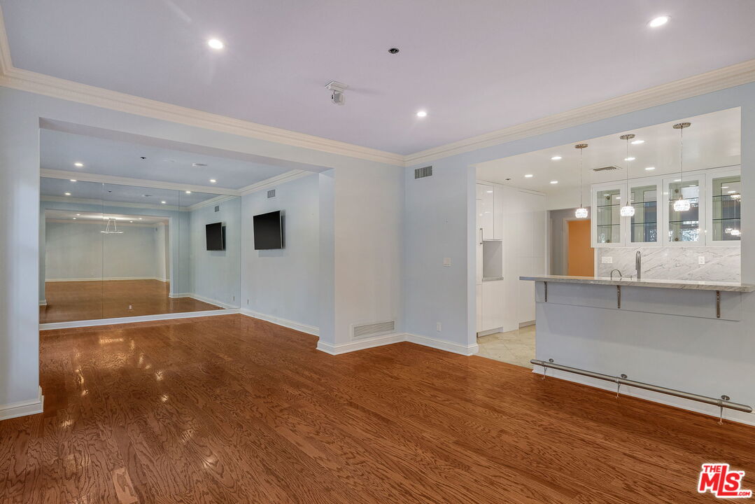 425 North Maple Drive, Unit 304 Beverly Hills, CA 90210 - Photo 9 of 26 a view of an empty room with wooden floor and a kitchen