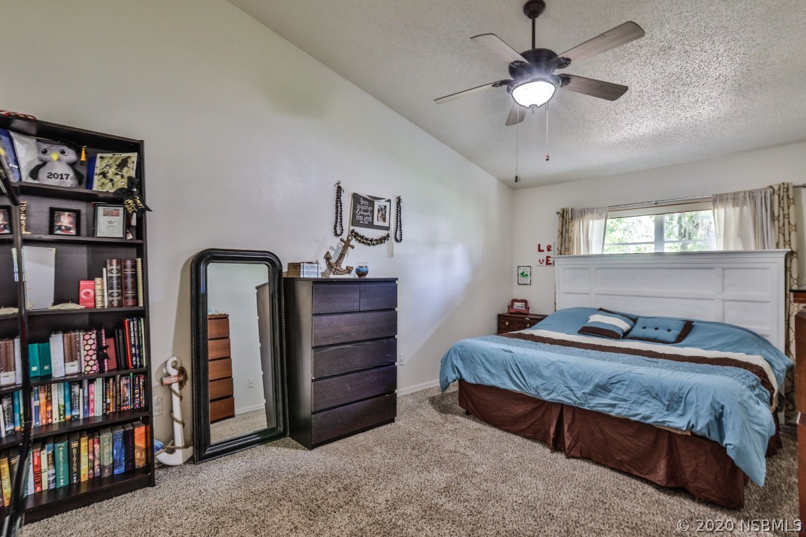 2103 Pine Tree Drive Edgewater, FL 32141 - Photo 23 of 26 a bedroom with a large bed a chandelier and book shelf