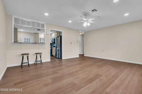 a view of an empty room with wooden floor and a ceiling fan