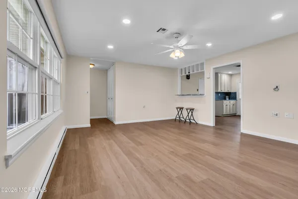 a view of an empty room with wooden floor and a window