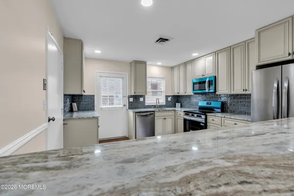 a kitchen with granite countertop a refrigerator and cabinets