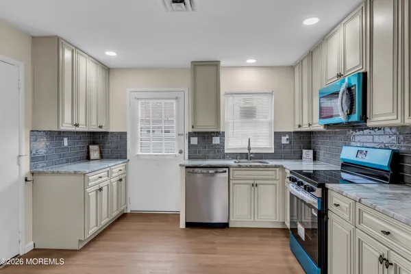 a kitchen with stainless steel appliances granite countertop a stove a sink and white cabinets
