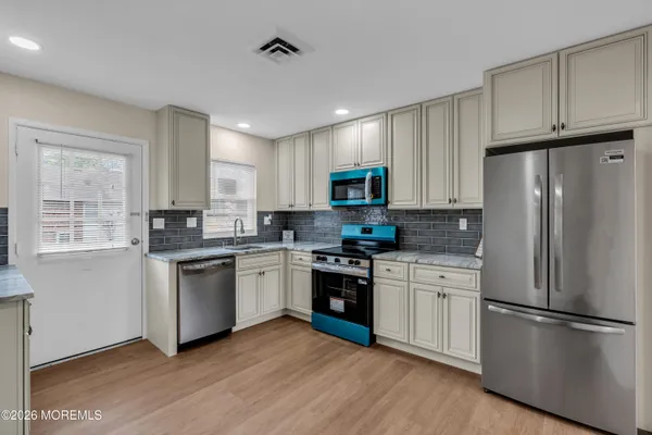 a kitchen with cabinets stainless steel appliances a sink and a window