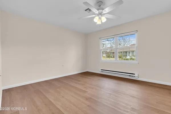 an empty room with wooden floor chandelier fan and windows