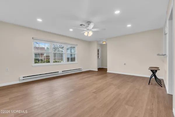 a view of an empty room with a window and wooden floor