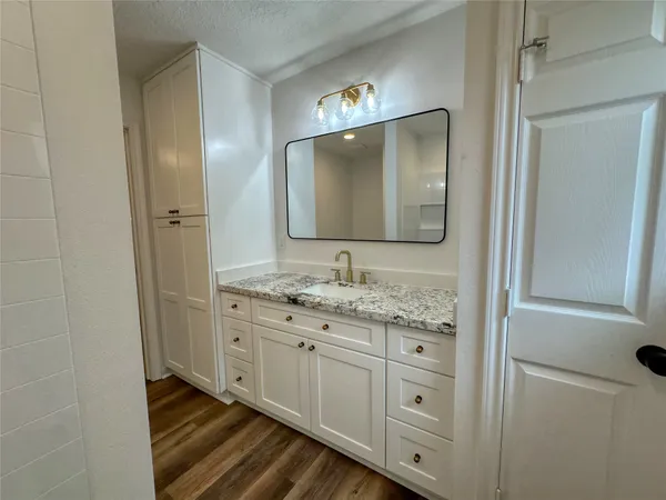 a bathroom with a granite countertop double vanity sink and mirror