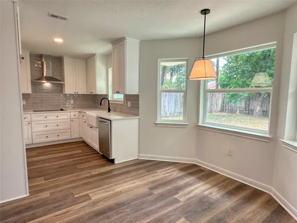 a kitchen with stainless steel appliances granite countertop a stove a sink dishwasher a refrigerator and a wooden floor