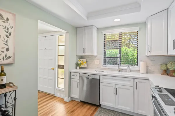 a kitchen with white cabinets and wooden floors