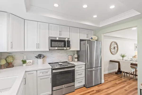 a kitchen with stainless steel appliances white cabinets and wooden floor