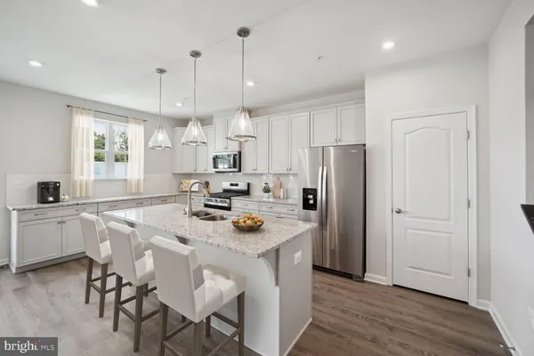 a kitchen with stainless steel appliances granite countertop a table chairs refrigerator and microwave