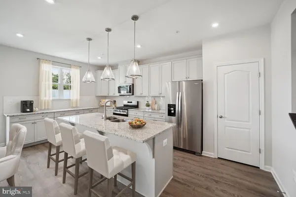 a kitchen with stainless steel appliances granite countertop a table chairs refrigerator and microwave