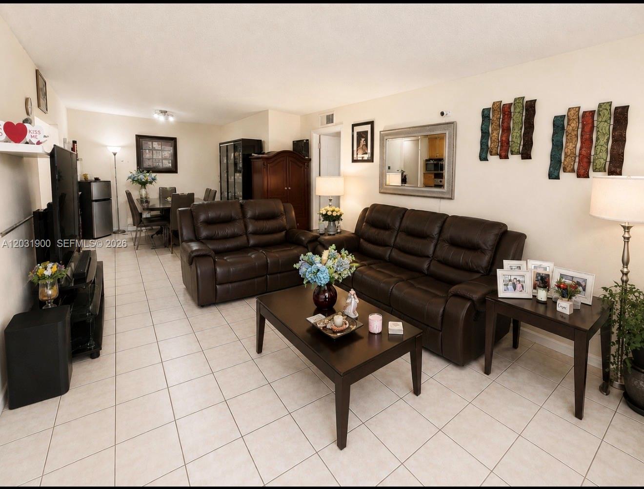 12860 Southwest 43rd Drive, Unit 146B Miami, FL 33175 - Photo 3 of 12 a living room with furniture a flat screen tv and kitchen view