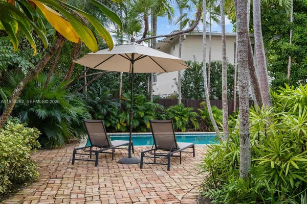 a backyard of a house with fountain table and chairs under an umbrella