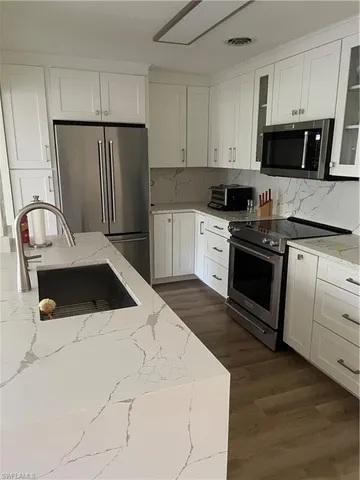 a kitchen with granite countertop white cabinets and stainless steel appliances
