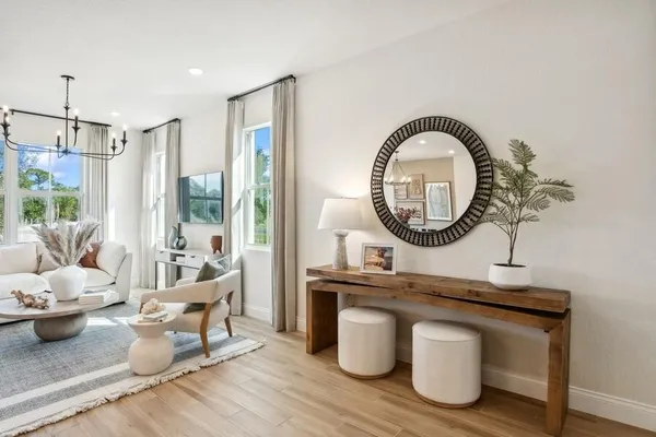 a living room with furniture a mirror a lamp and a large window
