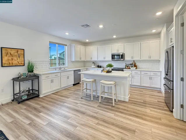 a kitchen with a sink a refrigerator and white cabinets