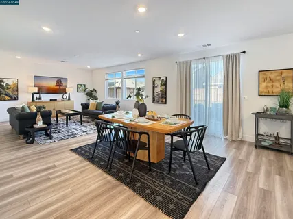 a open kitchen with stainless steel appliances granite countertop a dining table chairs and flat screen tv