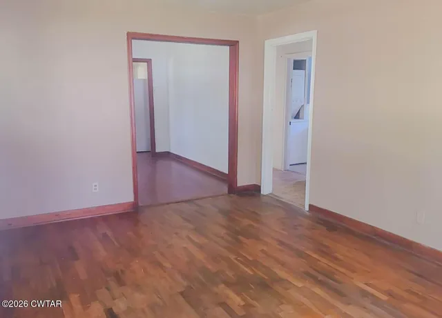 a view of an empty room with wooden floor and closet