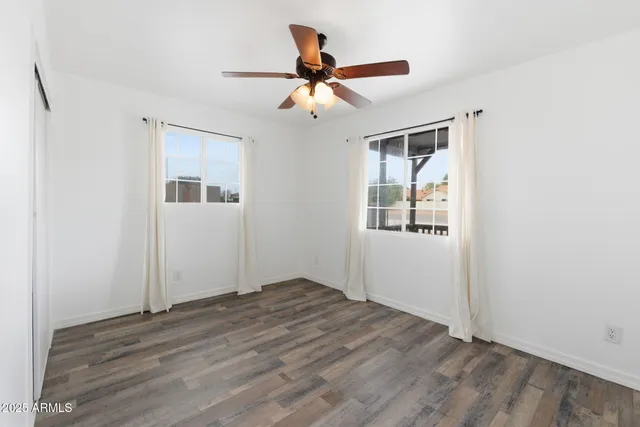 a view of empty room with wooden floor and ceiling fan