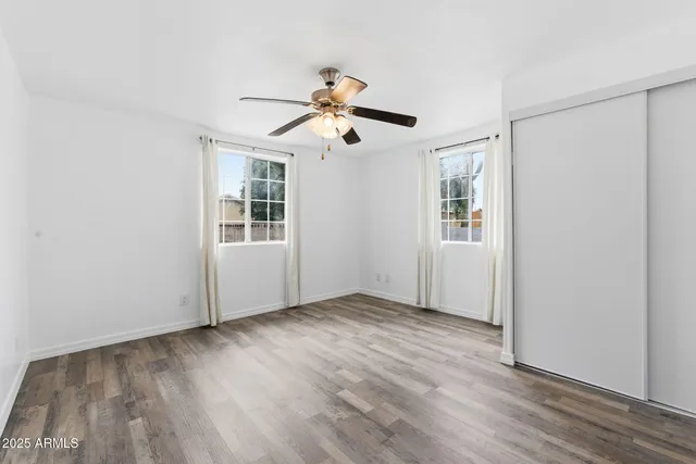 a view of an empty room with window and wooden floor